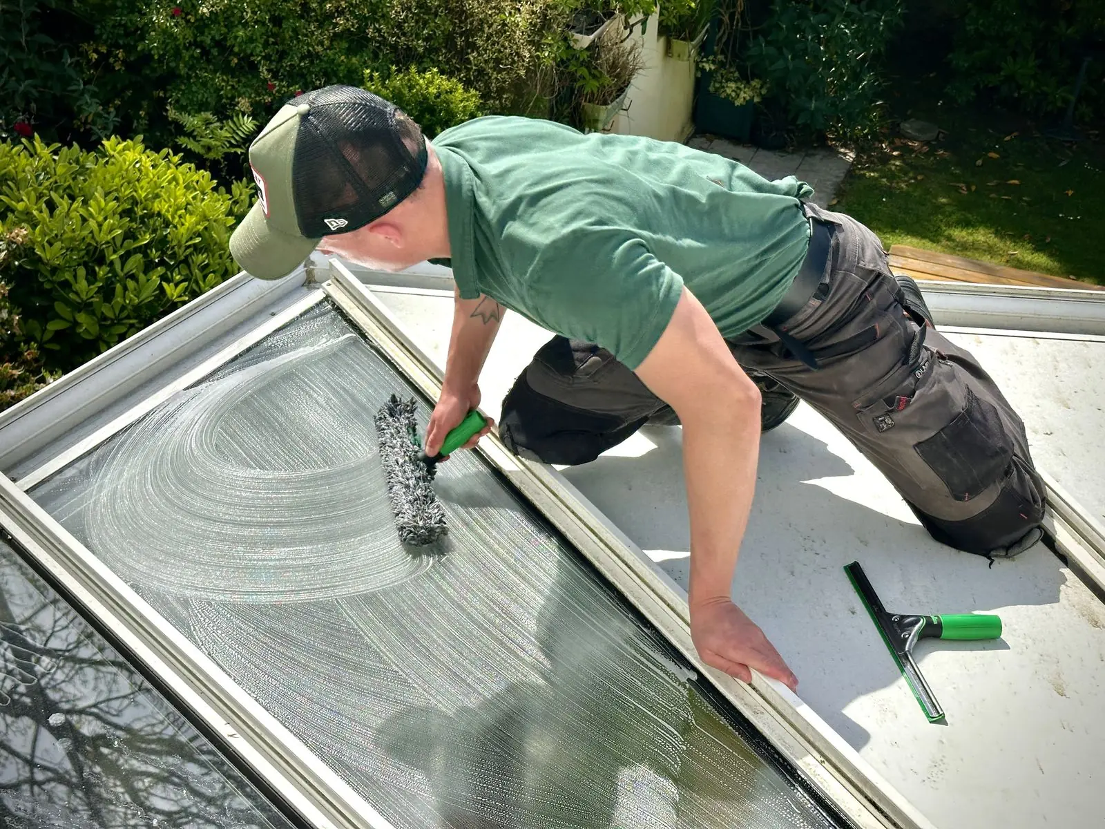 Anthony, laveur de vitres TONYCLEAN, lave une grande verrière d'angle près de Quimper